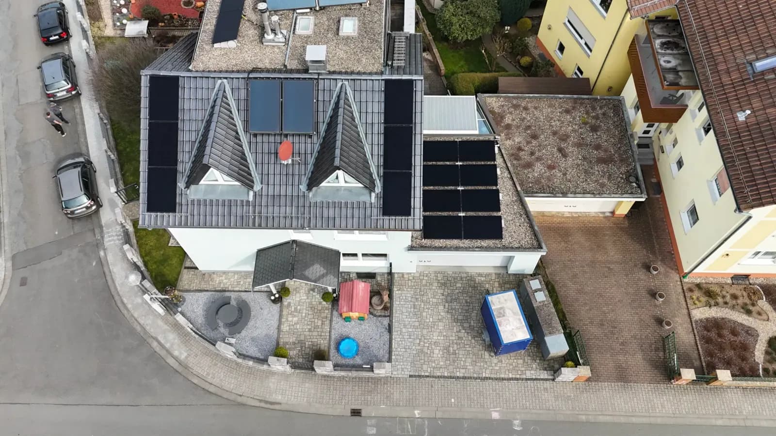 Dasselbe Anwesen aus schräger Drohnenperspektive mit Modulfeld auf dem flacheren Anbau