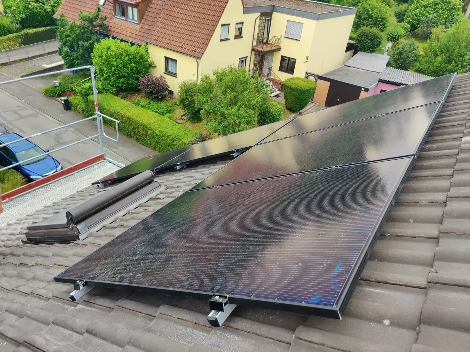 Einzelnes Modulfeld auf einem grauen Ziegeldach neben einem Dachflächenfenster