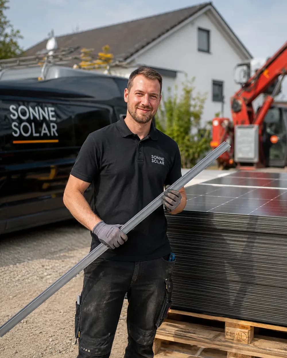 Daniel Ritter, Monteur bei Solartechnik Odenwald, mit einer Montageschiene neben gestapelten Solarmodulen